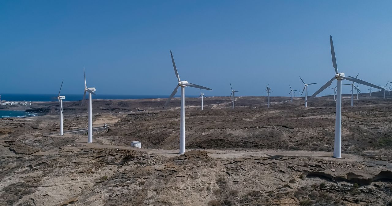 Mastering the First Impression: Your intriguing post title goes here Wind turbines on a barren coast, harnessing renewable energy under a clear blue sky.